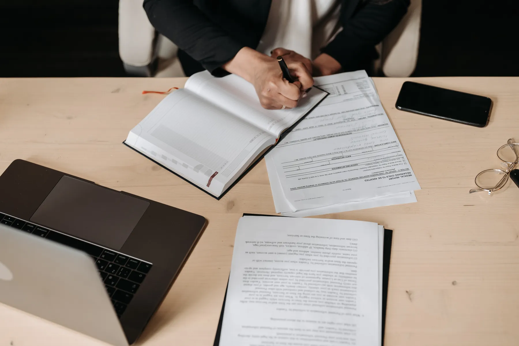 A recruiter annotates application documents beside a laptop.